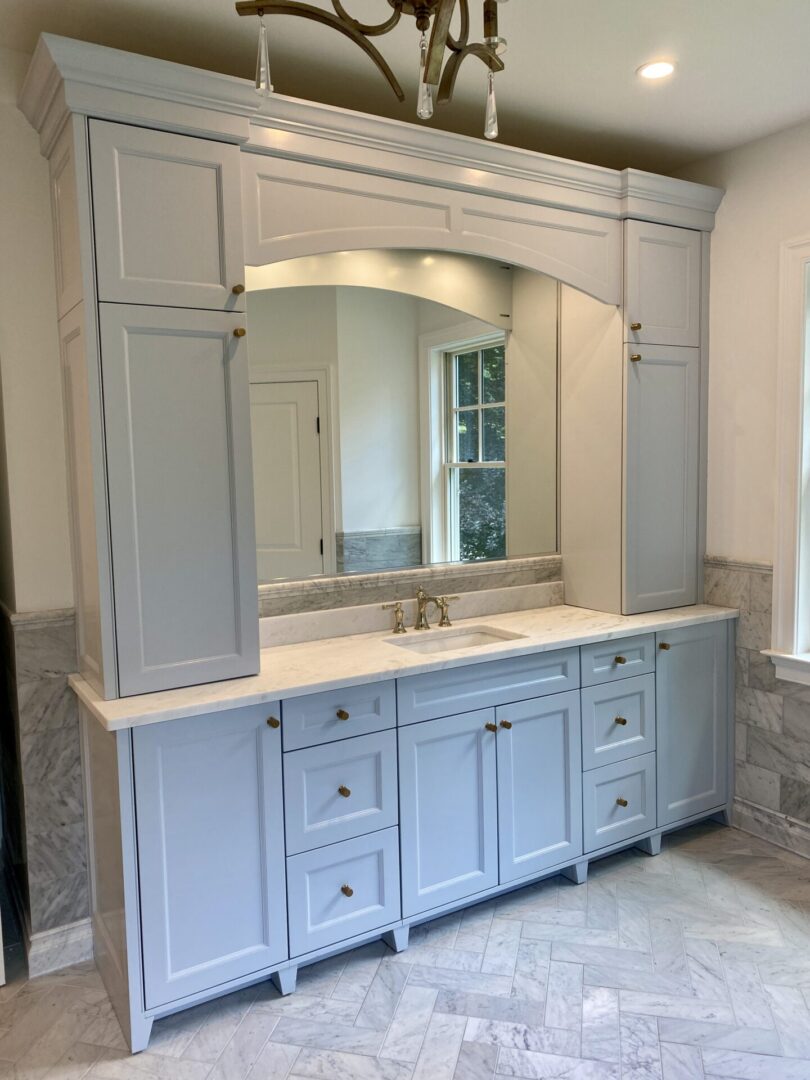 A White Cabinet Space With a Mirror Around a Sink