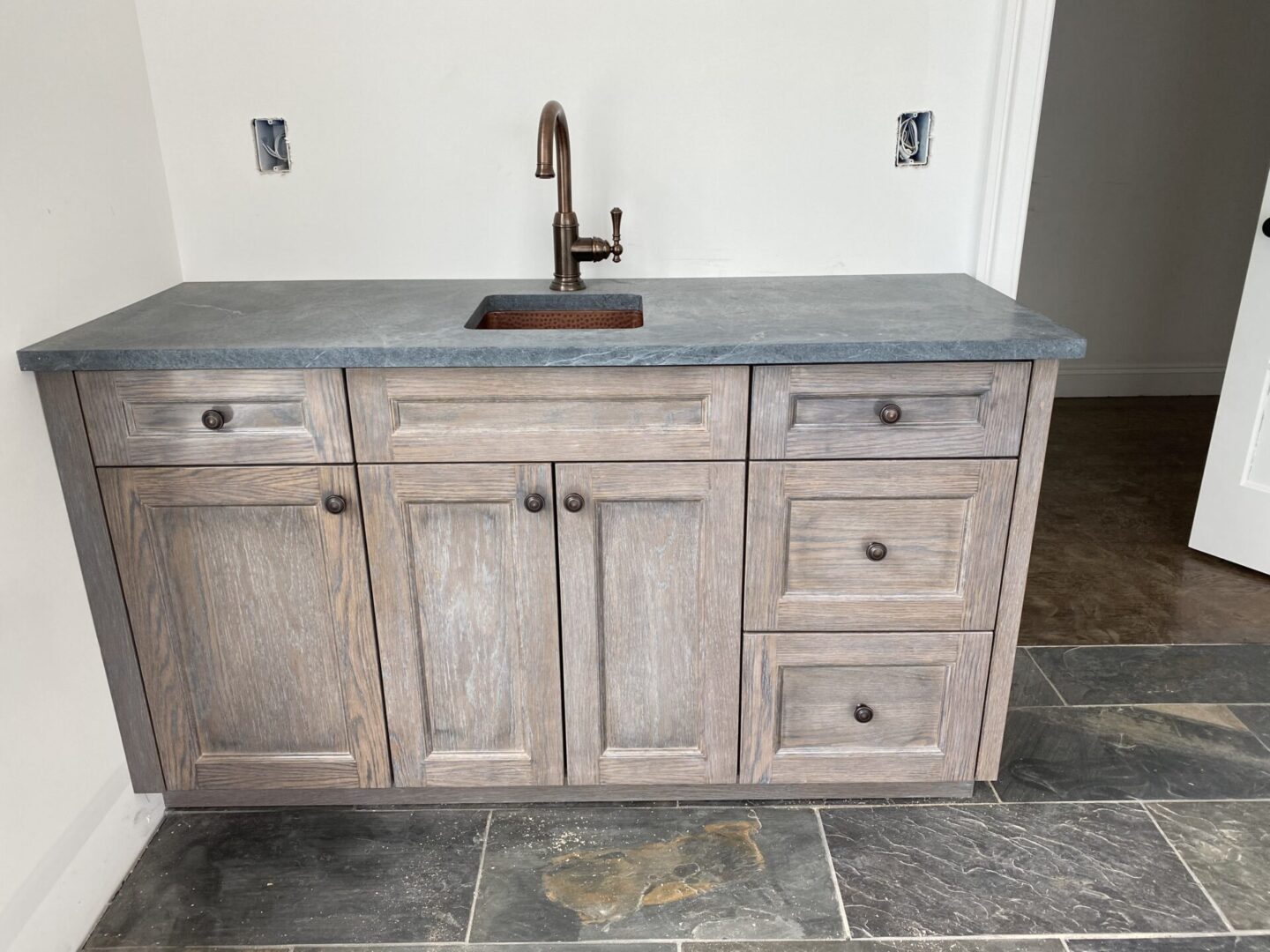 A sink under construction with gray marble and white interiors
